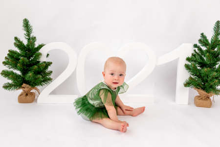 Christmas photo small child girl sitting near Christmas trees and numbers 2021 on a white isolated background, happy new year 2021, space for text.の写真素材