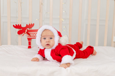 baby 6 months in a Santa costume lying in a crib at home on his stomach, a gift for the new year....