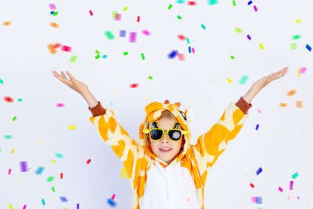 little boy in a fun bright giraffe costume on a white isolated background with confetti, children's birthday, place for textの写真素材