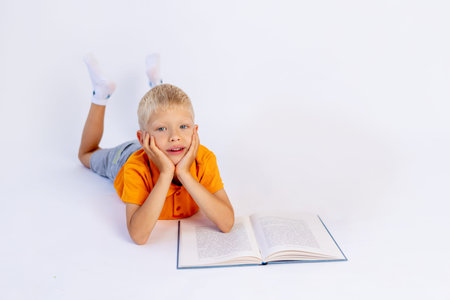 a small boy in an orange t-shirt reads a book on a white isolated background, preschool education,...