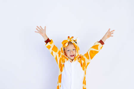 a cheerful boy in a bright orange giraffe costume held up his hands against a white isolated background, a place for textの写真素材