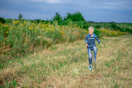 happy baby boy running across the field in summer, a child's lifestyleの写真素材