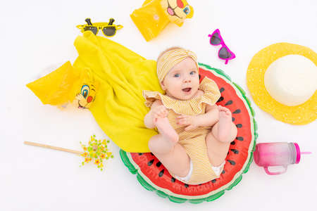 a smiling child with a swimming ring in a swimsuit, towel and sunglasses lies on a white isolated background. Holidays at sea with baby, conceptの写真素材