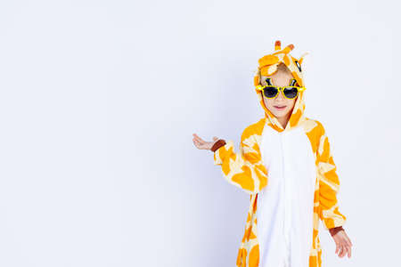 a cheerful boy in a bright orange giraffe costume holds his hand on a white isolated background, space for textの写真素材