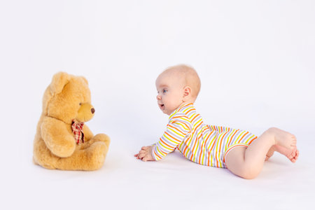 smiling baby girl 6 months old lies on a white isolated background in a bright bodysuit in front of...