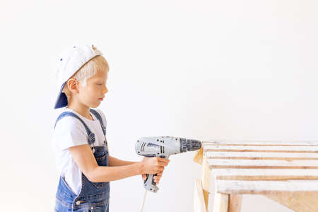 Little boy in a helmet plays in the builder with tools. isolated over white.の写真素材