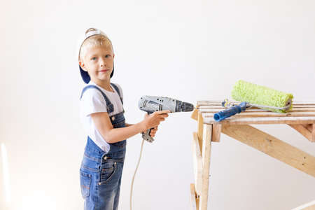 Little boy in a helmet plays in the builder with tools. isolated over white.の写真素材