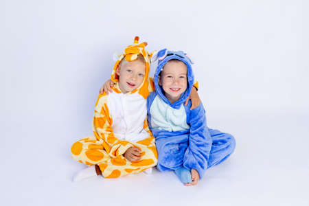 little boys brothers in fun bright costumes sit on a white isolated background, children's birthday, place for textの写真素材