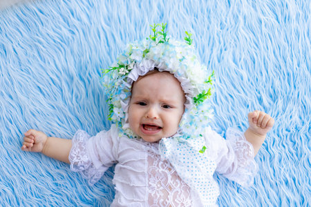 a little girl is lying on a blue fluffy rug in a hat made of flowers and crying