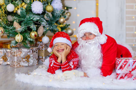 Santa Claus with a child near the Christmas tree huggingの写真素材