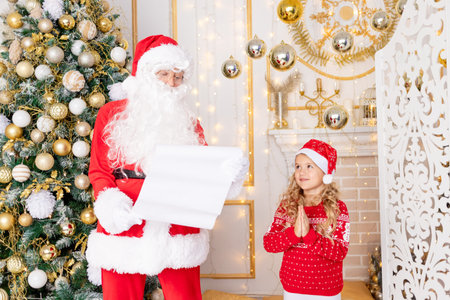 Santa Claus reads a letter from a child at the Christmas tree, new year and Christmas concept