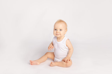 happy little child sitting on white isolated backgroundの写真素材