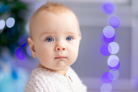 portrait of a small baby on a background of blue lights from a garland