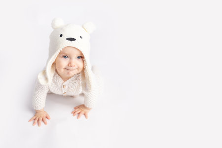 baby crawls in a warm suit and hat on a white isolated background, space for textの写真素材
