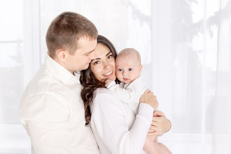 happy family mother and father hold a newborn baby at home, the concept of happy loving family,...