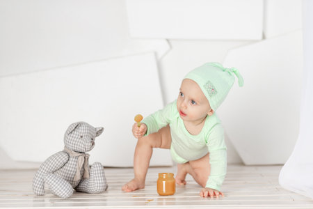 baby feeding spoon toy in green bodysuit, feeding and baby food conceptの写真素材