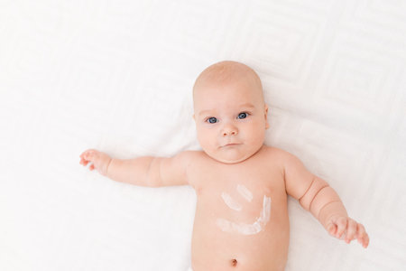 baby with a smile on his stomach on a light backgroundの写真素材