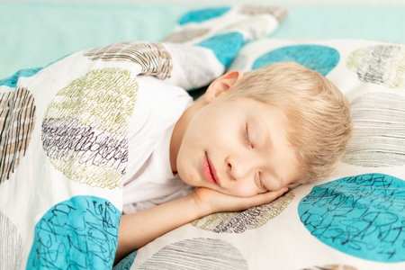 baby boy blonde sleeps in his bed at home.の写真素材