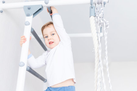 a child a boy does sports or exercises on the Swedish wall of the house