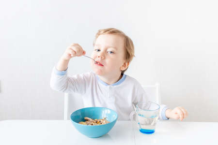 baby boy eats with a spoon at home, the concept of food and nutrition for childrenの写真素材