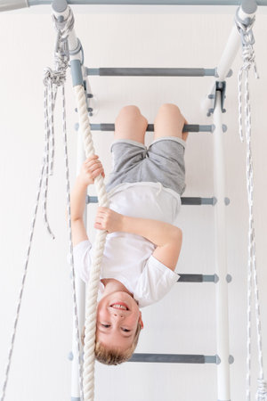 a child on the Swedish wall plays sports at home, a boy climbs a ladder with a rope, the concept of...