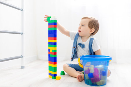 a child with a constructor at home, a cute boy plays or collects a colored constructor