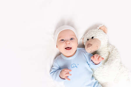 baby in the crib, portrait of a smiling baby 3 months in the crib with a teddy bear toy, children and birth conceptの写真素材