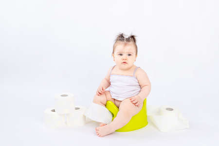 baby on a green potty with toilet paper on a white insulated background, space for textの写真素材