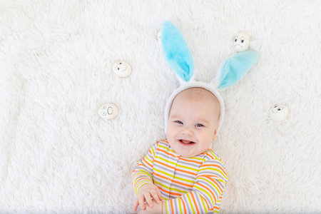 baby boy in rabbit ears on his head lies with eggs with emotions, cute funny smiling little baby....