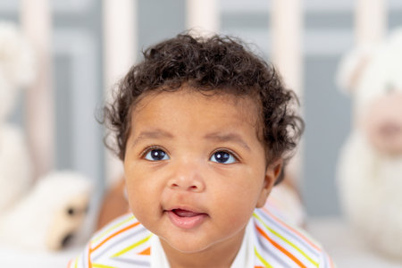 portrait of a smiling African-American little baby in bed