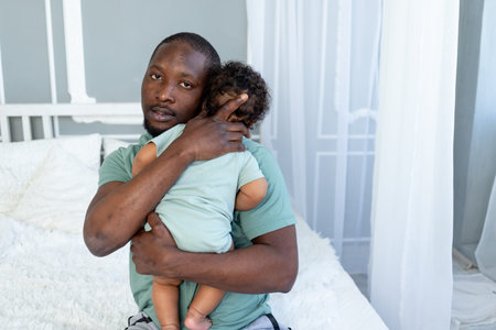African-American dad hugs baby son holding him at home, happy family, Father's Day