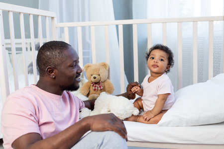 african-american family, dad and baby son talking or playing in the bedroom at home, happy father