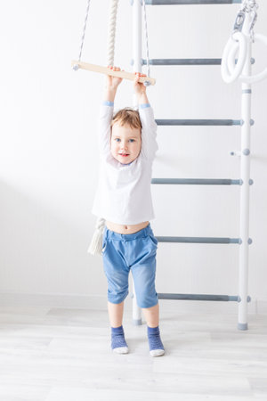 a child a boy climbs on the Swedish wall of the houseの写真素材