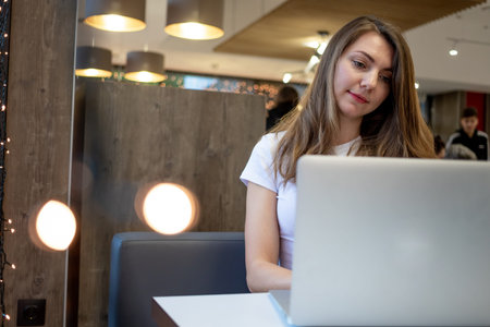 smiling freelance girl working at a laptop in a cafe, working day of a free young woman.