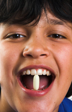 Smiling boy with a pill in his mouth