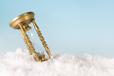 Antique hourglass timer lying in the snowの写真素材