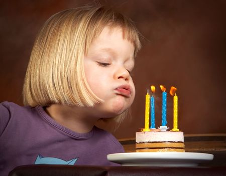 Little girl blowing candles on her birthday cakeの写真素材
