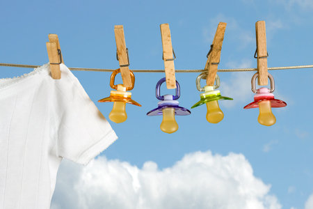 Row of pacifiers hanging next to baby laundry