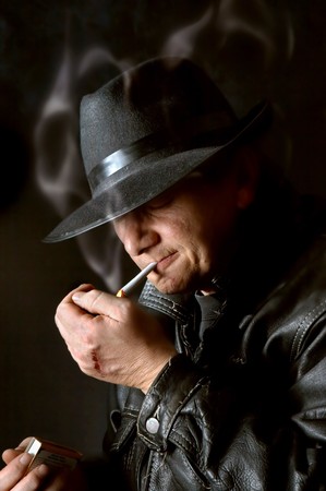 Mafia watchman lighting a cigarette in the darkの写真素材