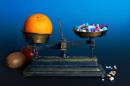 Balance weighing healthy food, fruit, and diet or vitamin pillsの写真素材