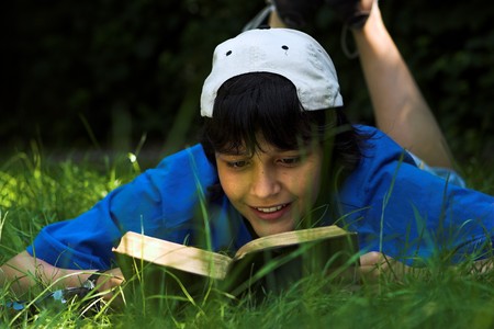 Boy reading in the park on a sunny dayの写真素材