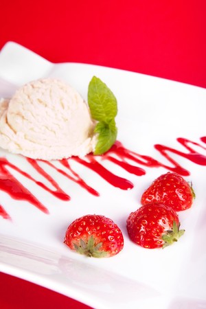 Fancy dessert with vanilla ice cream, strawberries and raspberry sauceの写真素材