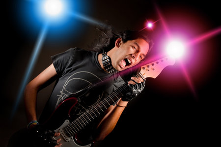 Young handsome rock singer against a dark background with spot lights