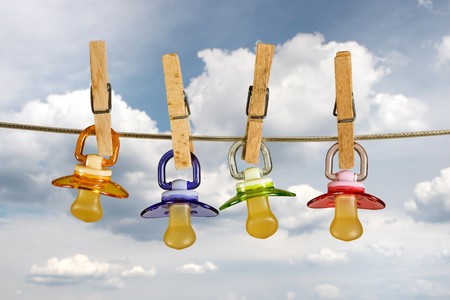 Colored baby pacifiers hanging outside in lineの写真素材