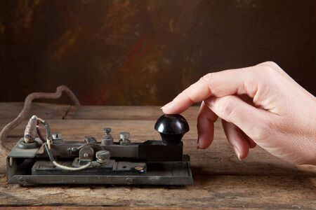 Hand tapping morse code on an antique telegraphの写真素材