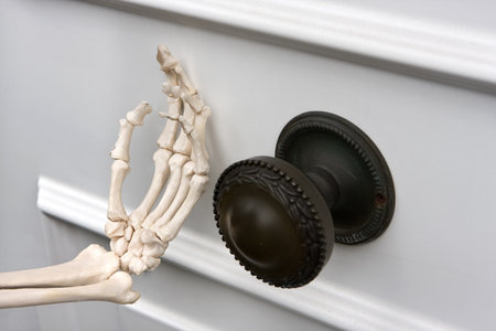 Hand of death knocking on a white front doorの写真素材