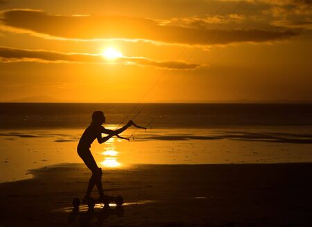 Silhouette of a kiter against a smashing beach sunsetの写真素材
