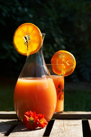 Pitcher with orange juice or lemonade and a glass with a straw