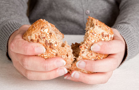 Hands of a woman breaking and sharing bread