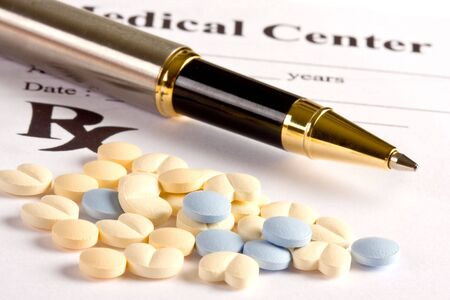 Several little pills and a pen lying on a prescription documentの写真素材